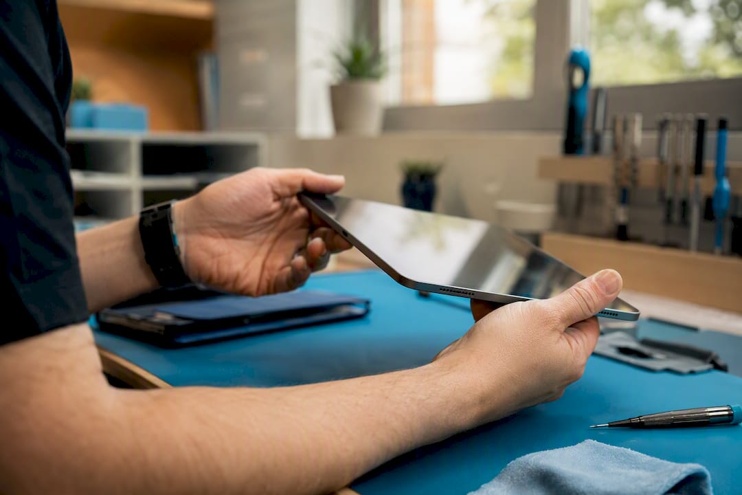 Hands inspecting refurbished tablet edges and screen