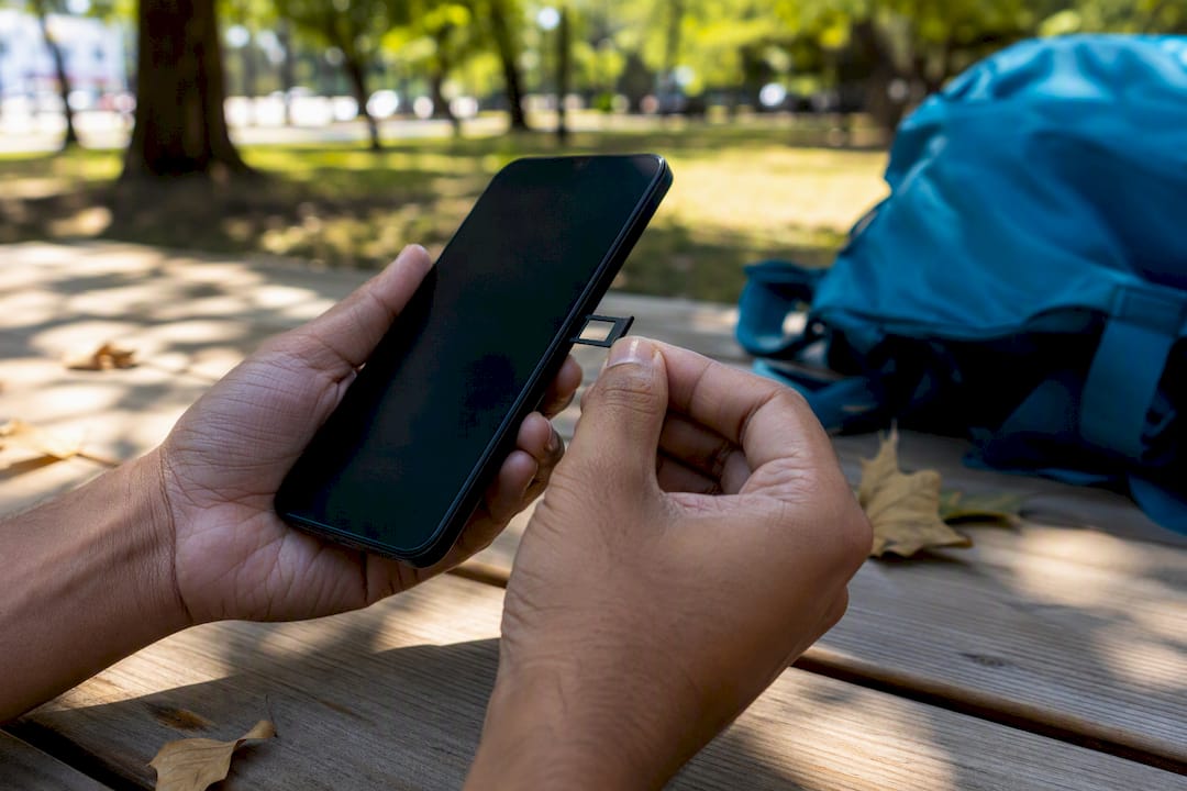 Hands checking phone IMEI with SIM card tray open