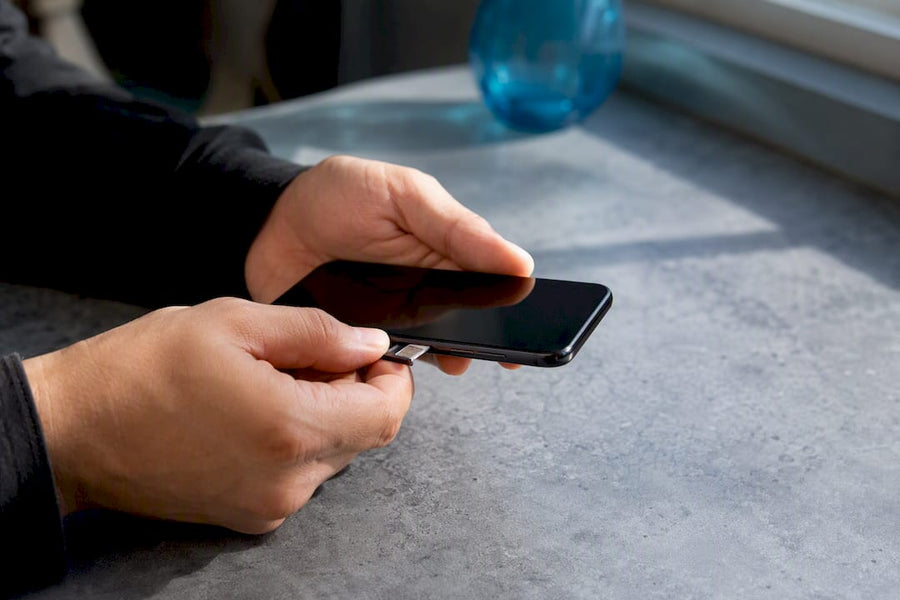 Hands opening SIM tray on smartphone