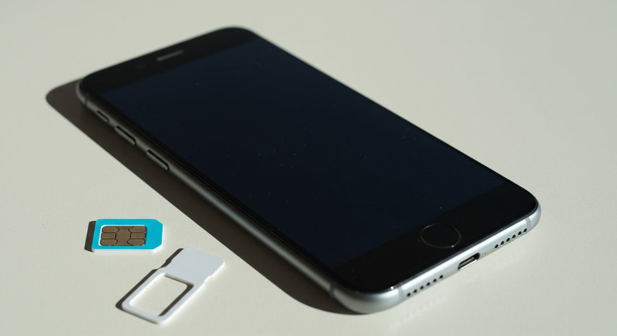 An unlocked iPhone next to a SIM card and eject tool